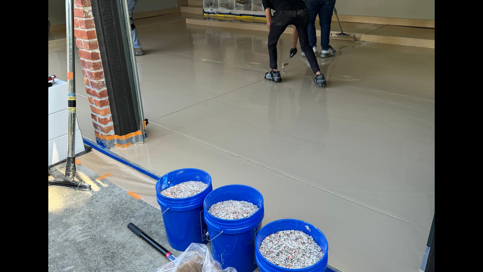 Reserve Coatings crew applying epoxy base coat in a residential garage